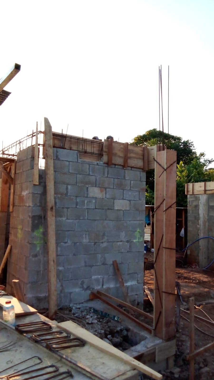 Se observa una estructura de bloques de concreto en construcción con encofrados de madera y varillas de acero expuestas.