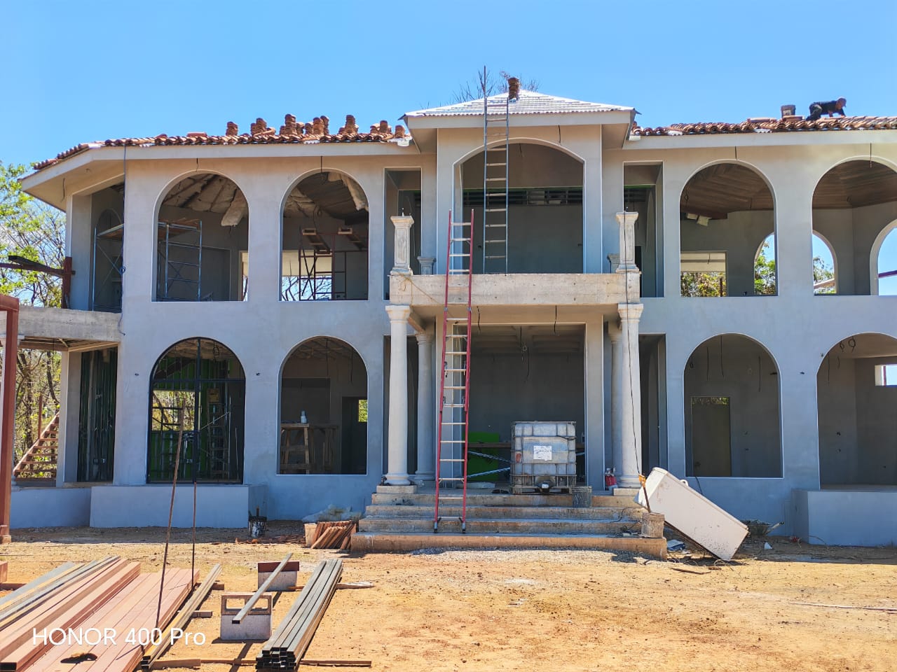 Una casa grande en construcción con arquitectura de arcos y columnas en proceso de acabado.