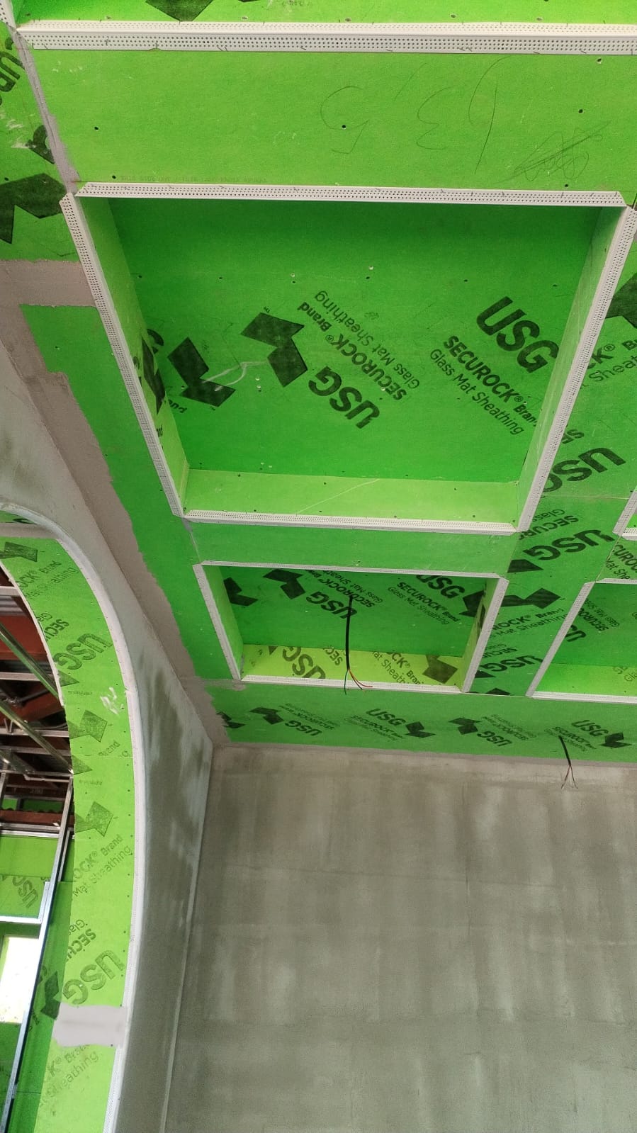 Se observa una estructura de techo en construcción utilizando paneles de yeso verdes de la marca USG Securock.