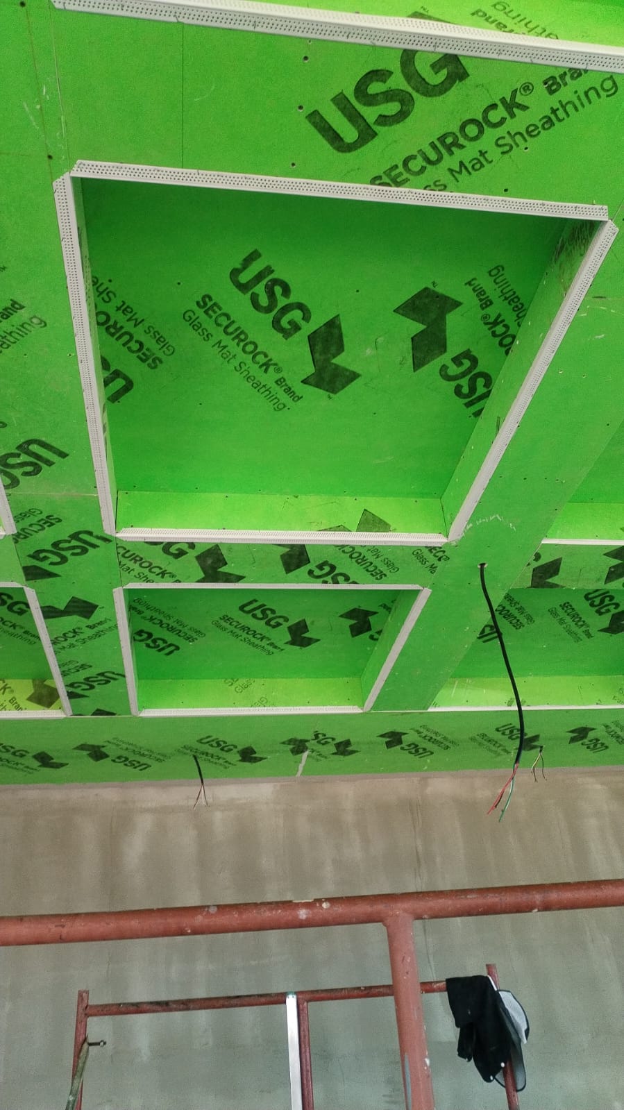 Se observa una estructura de techo en construcción utilizando paneles de yeso verdes de la marca USG Securock.