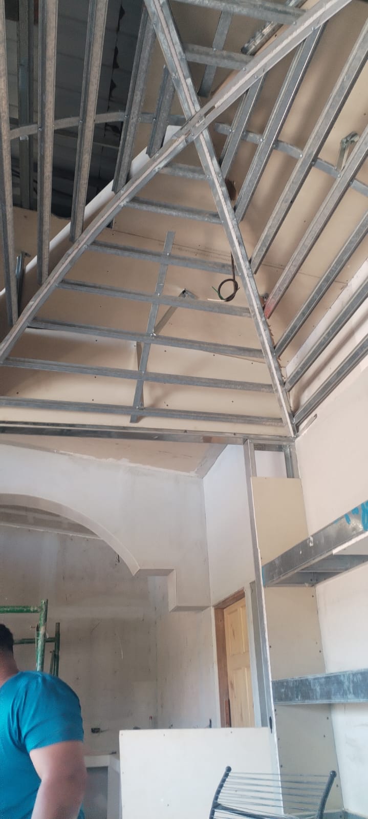 Se observa una estructura de metal para cielo raso en proceso de instalación dentro de una construcción.