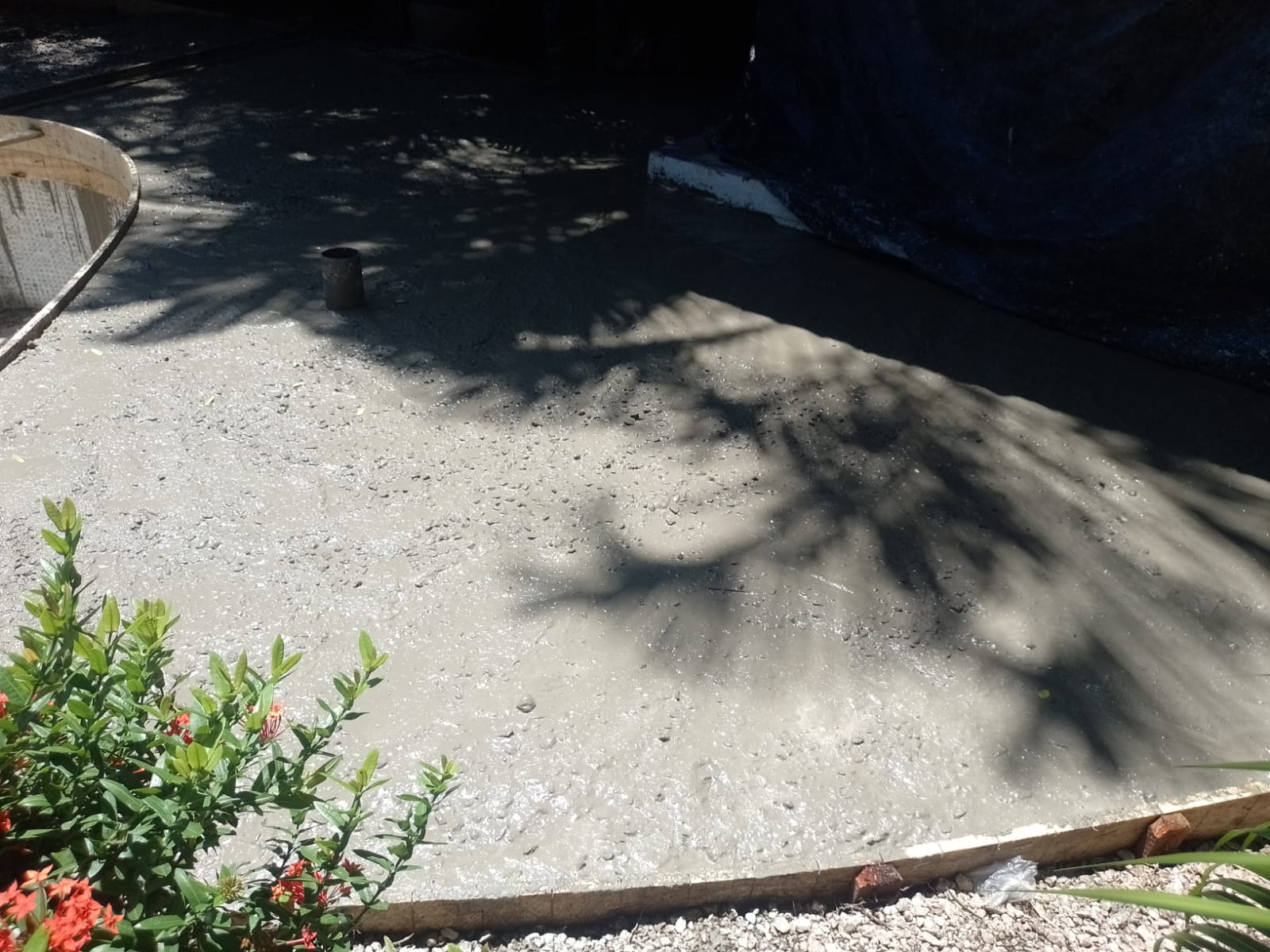 Se observa una superficie de concreto fresco recién vertido en un área de construcción al aire libre.